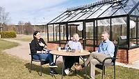 En man och två kvinnor sitter vid ett bord utanför ett växthus