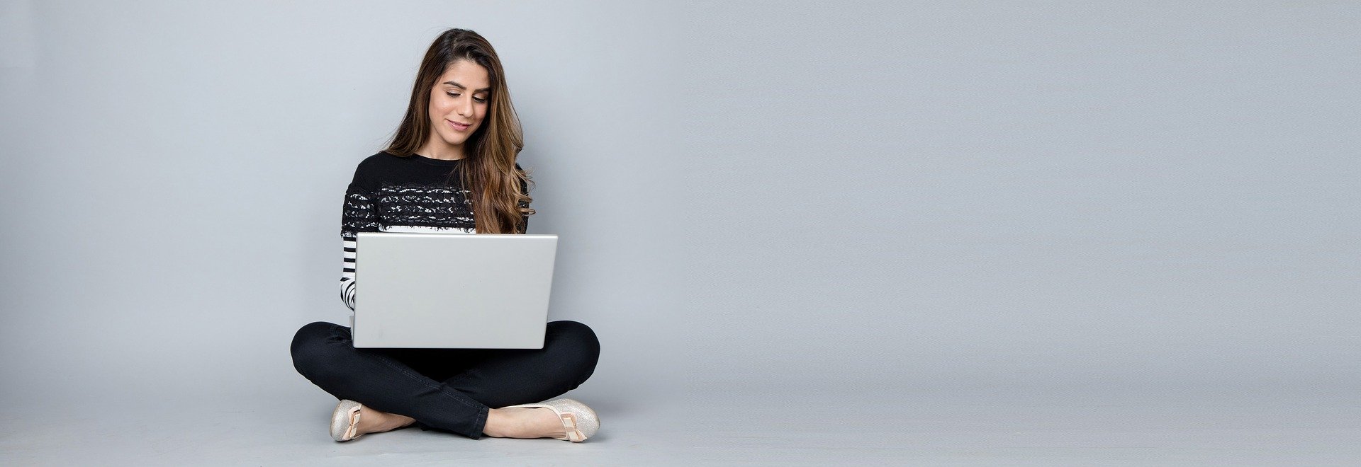 Bild på en kvinna som sitter på golvet med en bärbar dator