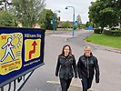 Två kvinnor promenerar undner skylt med texten "Hälsans Stig"